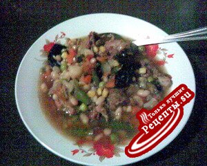 Говяжий суп с фасолью, овощами и черносливом в керамической посуде
